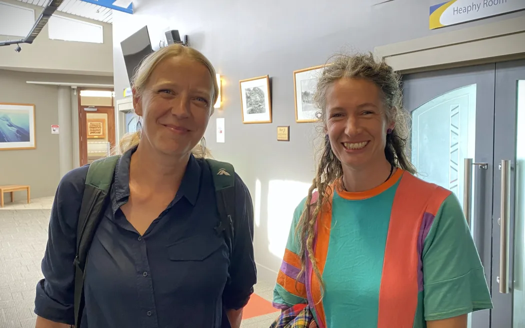 An image of Femke Meinderts (left) with a blond hair and a long sleeved button down and backpack and Emily Osborne (Right) with blond hair and a patterned green an orange shirt.