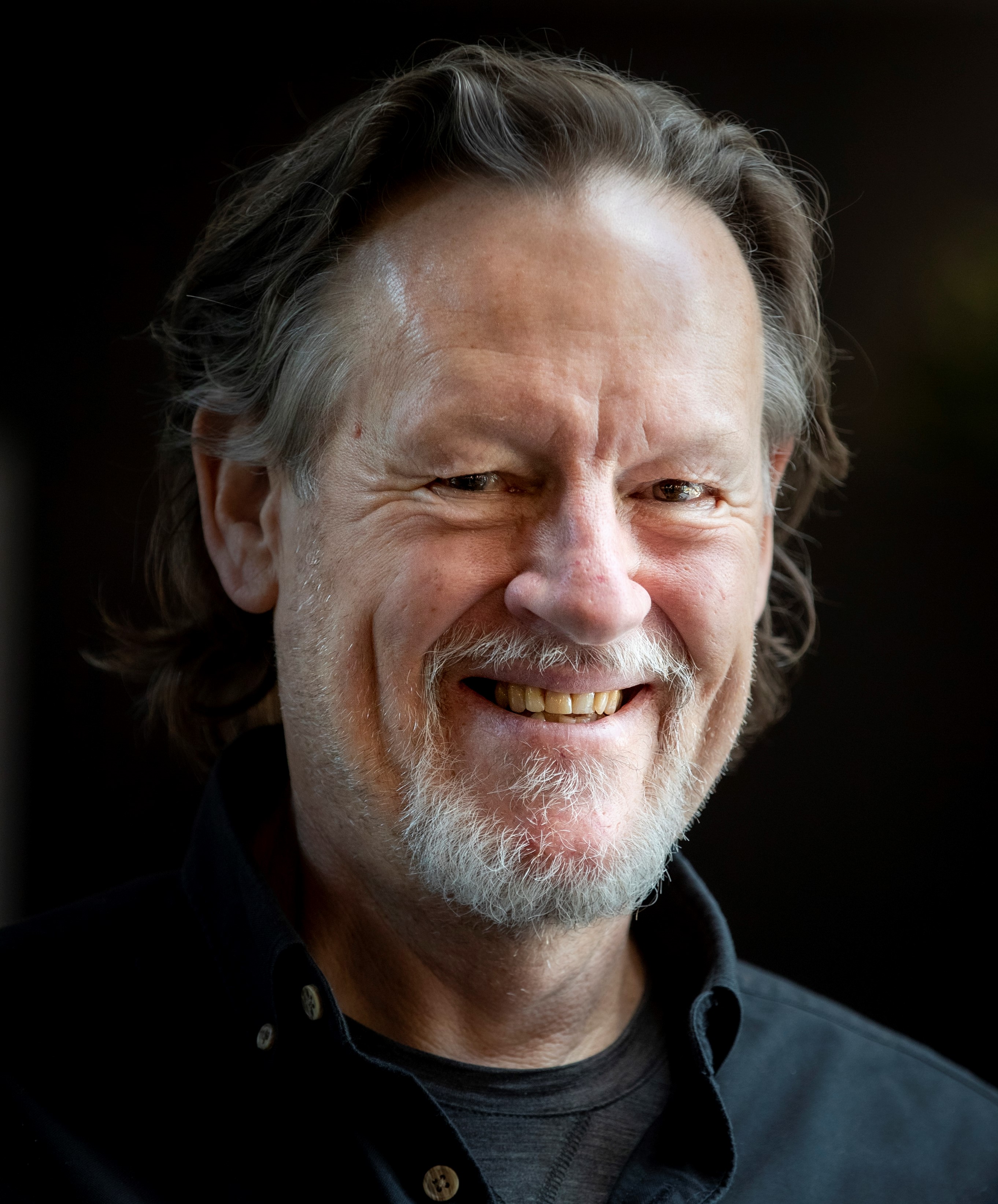 An image of Simon Wilson with salt and pepper hair and grey mustache and beard.