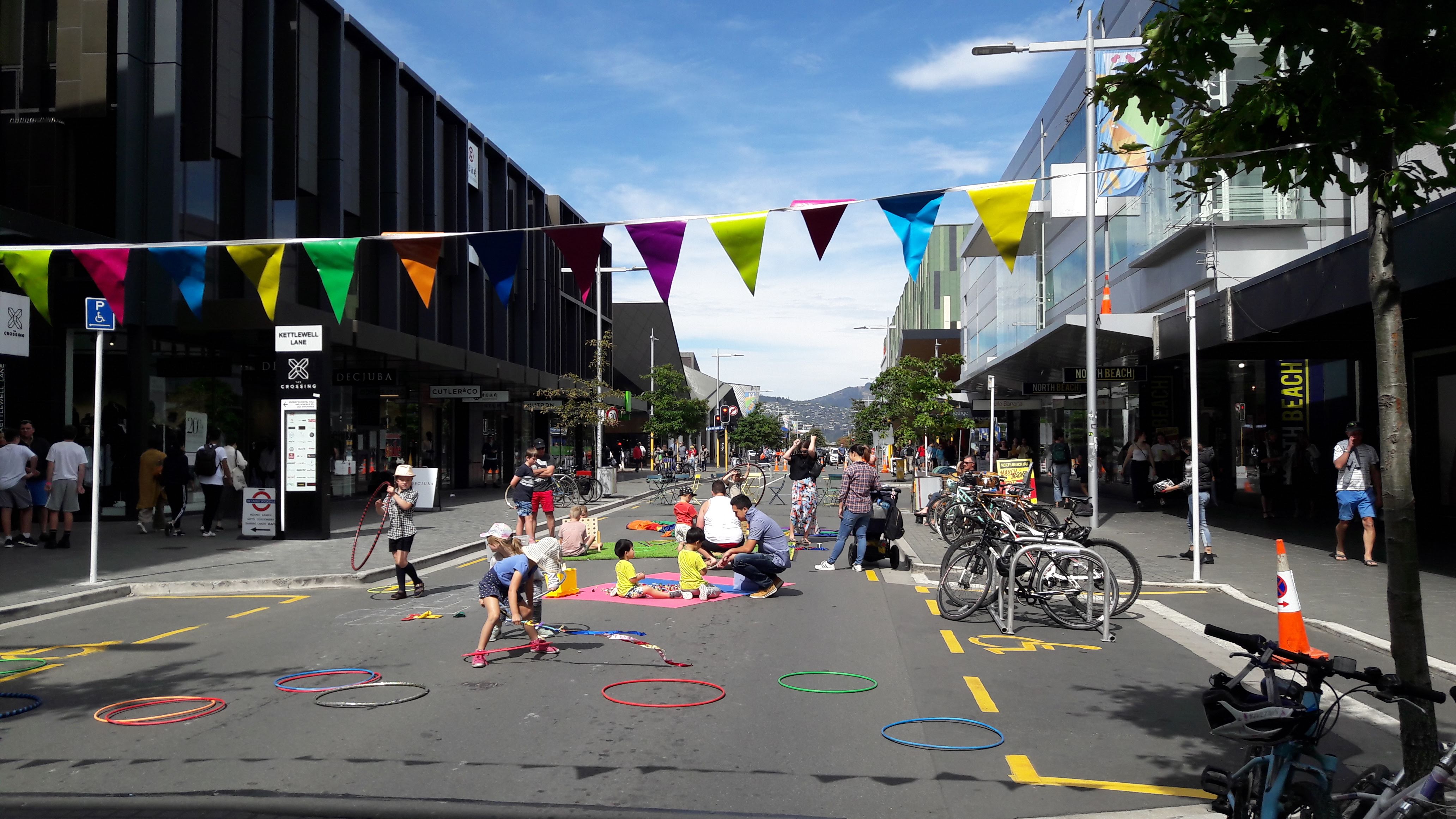 Street closed to traffic with children and parents playing with toys and people walking