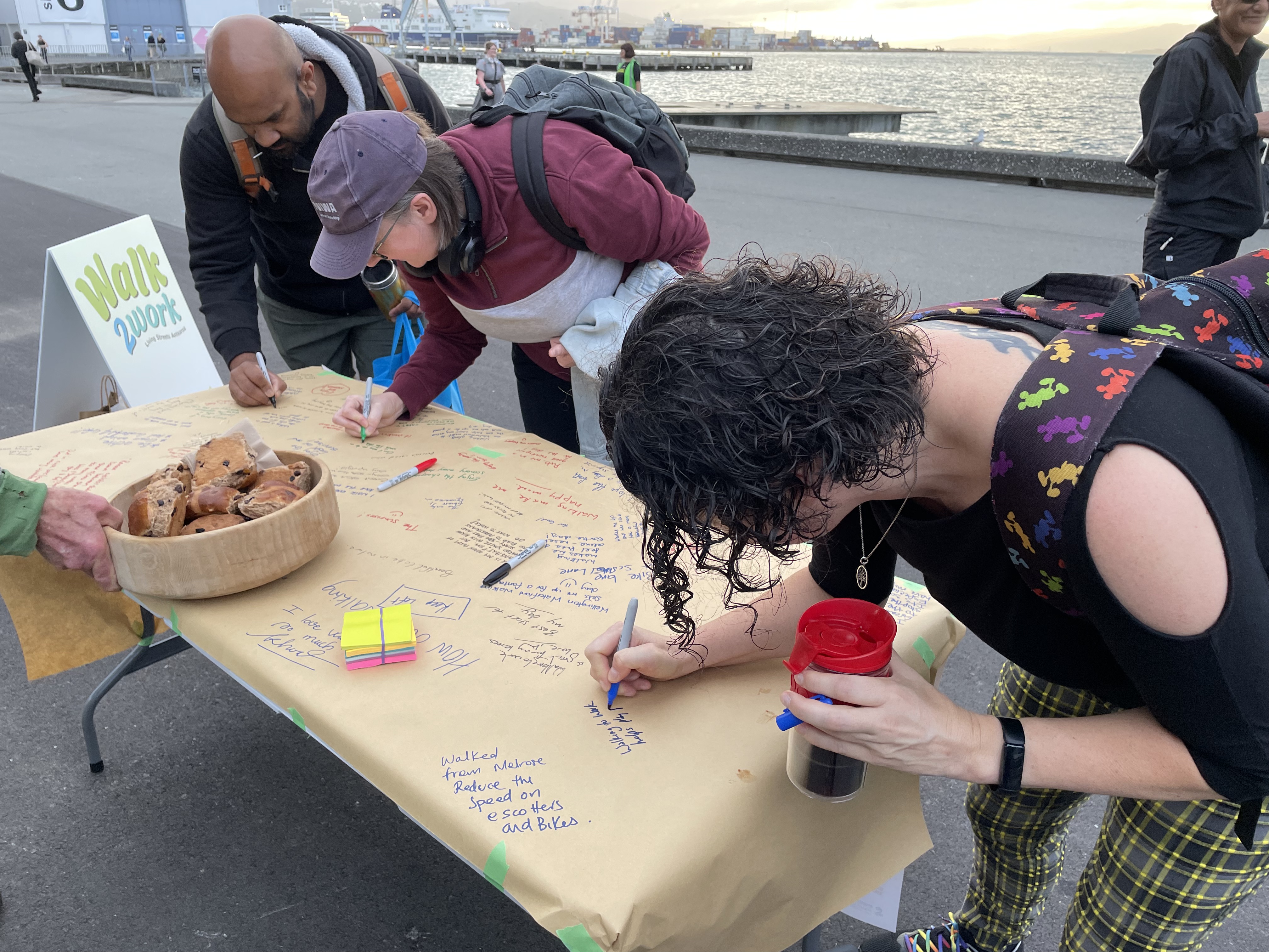 People writing comments on a large piece of paper on a table. 